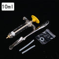 10ml syringe with plunger, metal tool, and small plastic bag on a black background