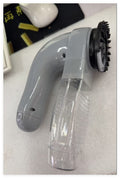 Gray handheld cleaning tool with bristle head on a white surface